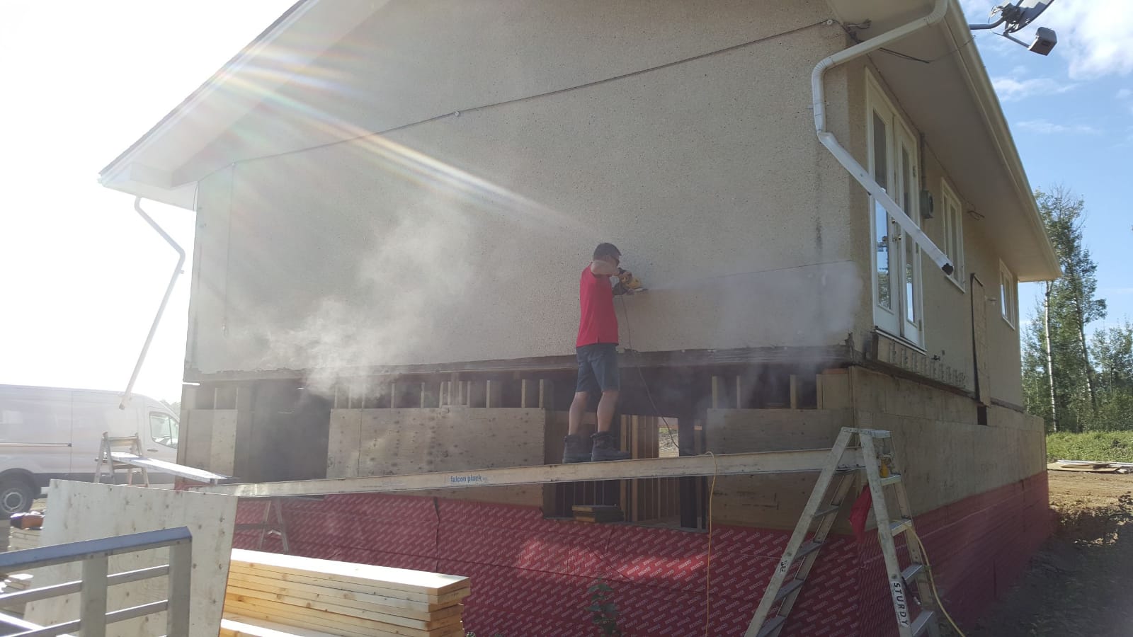 man working on house siding on ladder in red deer