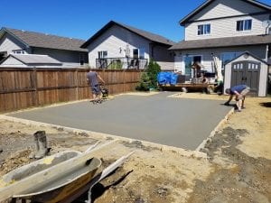 two men working in shorts house backyard patio cement in red deer